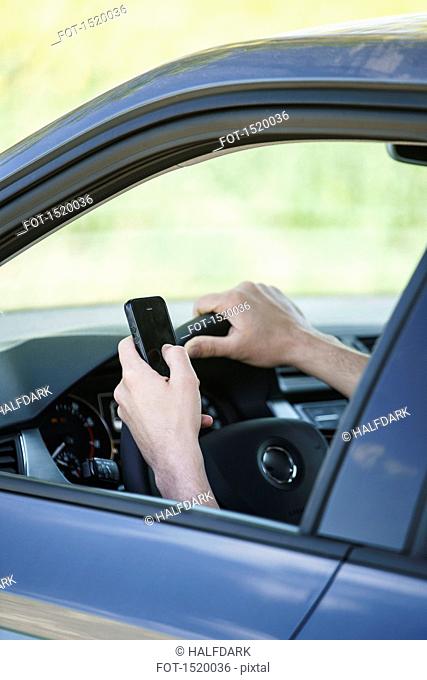 Cropped image of hand using smart phone in car