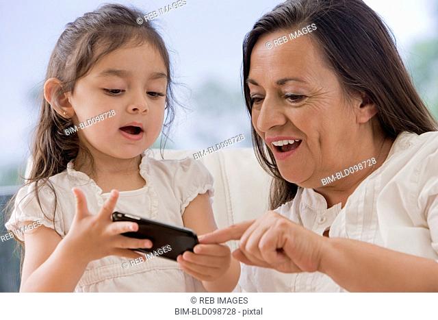 Hispanic grandmother showing cell phone to granddaughter
