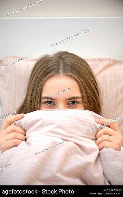 Young woman Hides under blanket