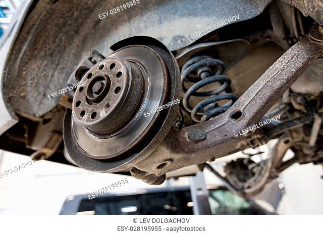 auto service and maintenance concept - car brake disc at repair station