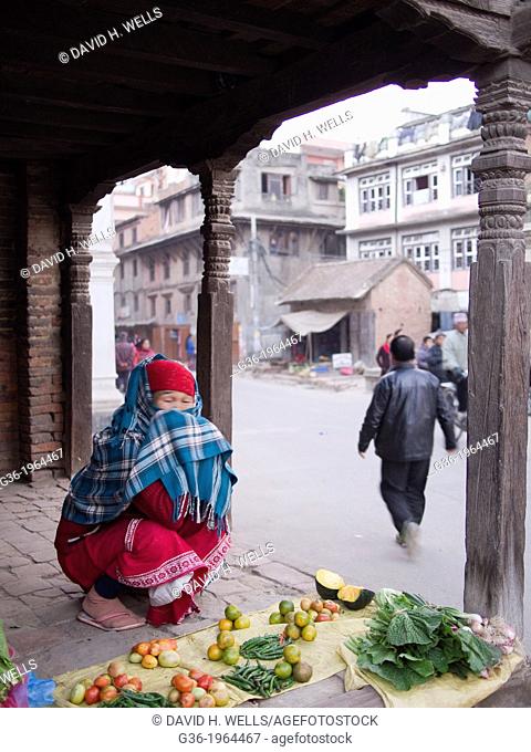A young person sits by the vegetables they are selling outside in Patan, Nepal