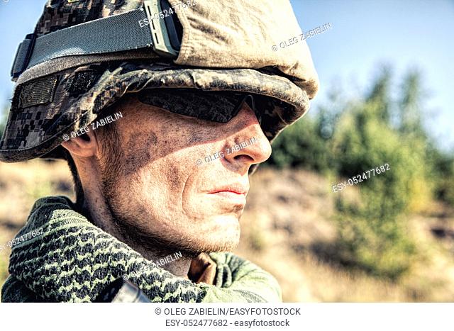 Location shot of United States Marine with rifle weapons in uniforms. Military equipment, army helmet, warpaint, smoked dirty face, tactical gloves