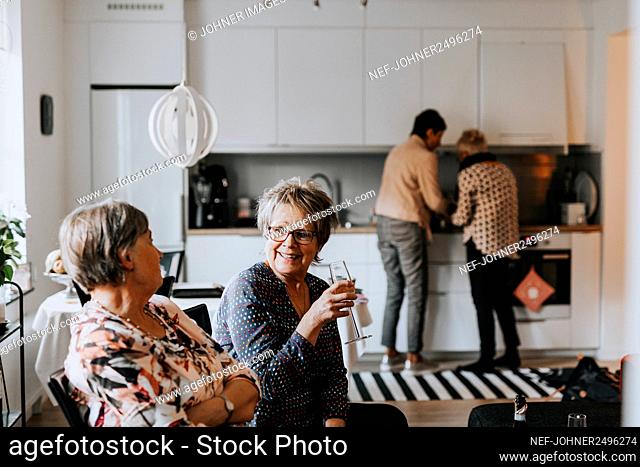 Senior friends talking together in kitchen