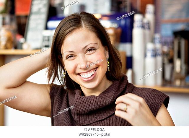 Portrait of happy young woman with hand behind head at cafe