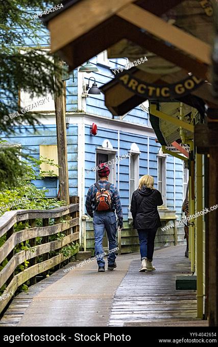 Couple walking down boardwalk on historic Creek Street in Ketchikan, Alaska, USA