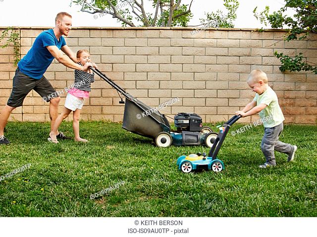 Family mowing lawn in backyard
