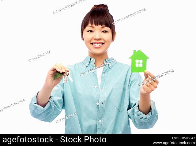 smiling asian woman holding green house and keys