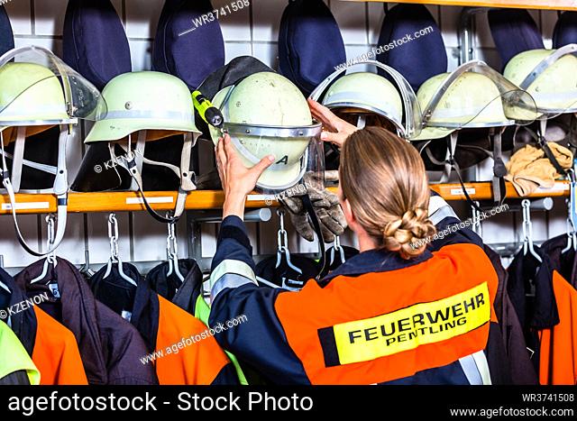 Female fire fighter in the locker room taking helmet in fire alert situation