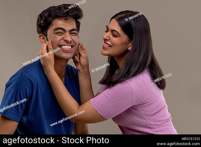 A YOUNG WOMAN CHEERFULLY TEASING YOUNGER BROTHER