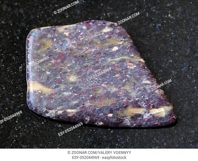 macro shooting of natural mineral rock specimen - polished Alunite stone on dark granite background from Zaglik, Dashkasan region of Azerbaijan