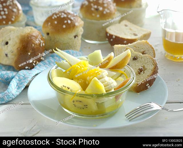 Fruit salad in a small bowl, with homemade raisin rolls