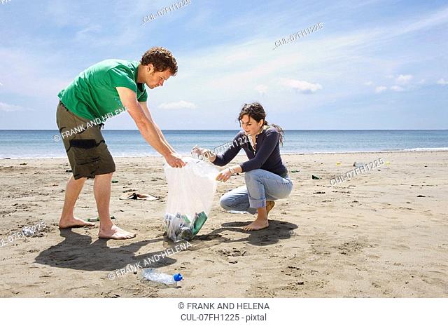 Young couple collecting garbage on beach
