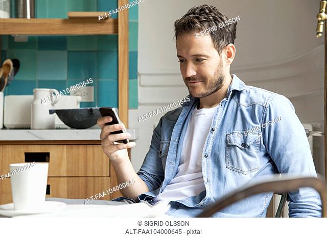 Man reading news on smartphone while having breakfast