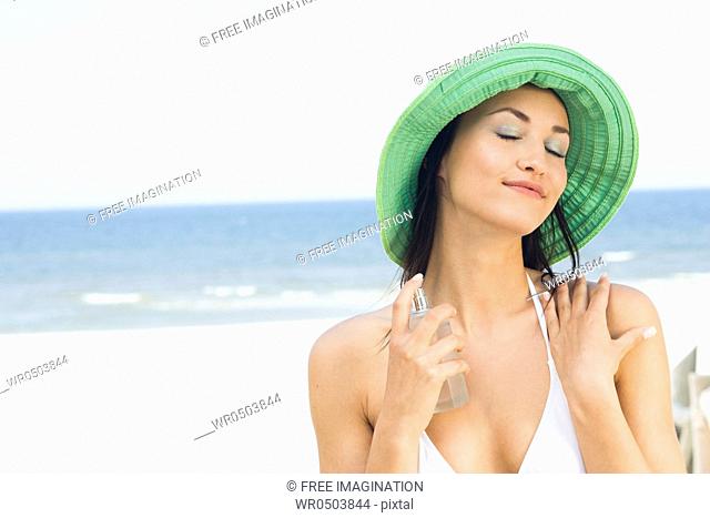 woman applying perfume on beach