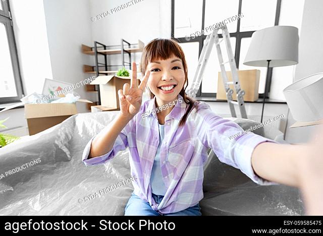smiling asian woman taking selfie at new home