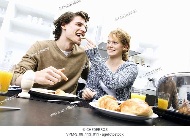 Young woman feeding a young man a slice of bread