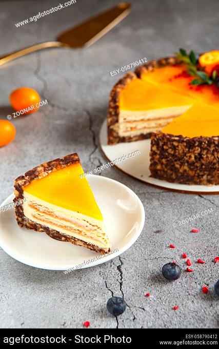 Cheese cake with mango fruit on a grey background. Cheese cake with passion fruit sauce on top, decorated with berries and fruits