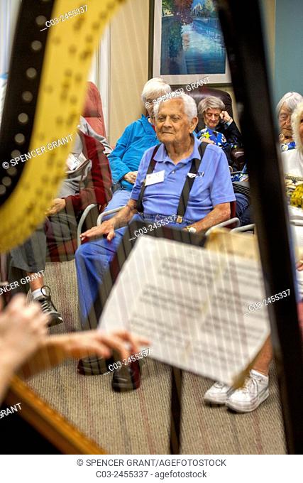 An elderly audiences listens to a harp and flute classical music concert at a Southern California retirement community