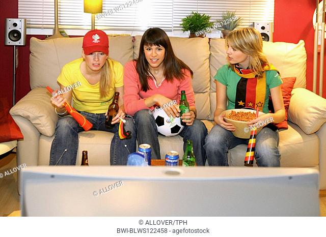 women, football fans excited in front of television