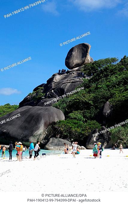08 March 2019, Thailand, Similan: Tourists walk on the beach of the ""Ao Kuerk"" bay of the island Ko Similan. In the background you can see the rock formation...