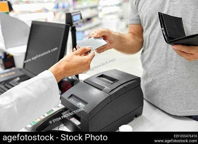 close up of hand giving bank card to pharmacist