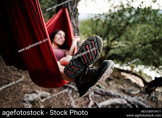 Woman relaxing on hammock in forest during vacation