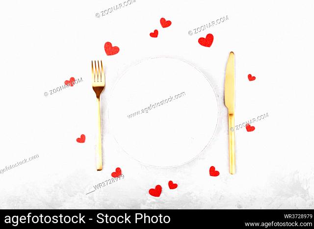 Romantic table setting with golden cutlery on white stone table.Valentine's day card template
