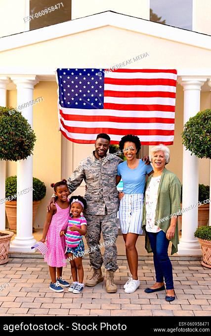 Portrait of smiling african american family with army soldier at entrance against usa flag