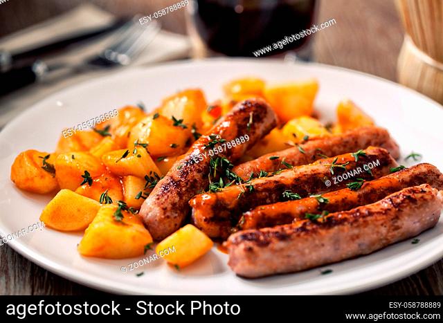 Sausages and roasted potatoes on a plate. High quality photo