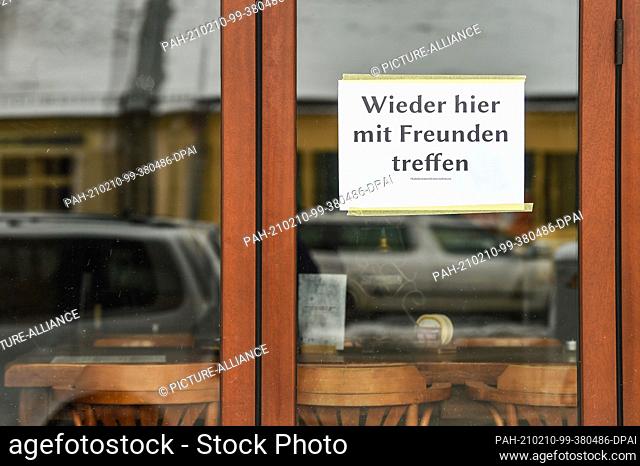 10 February 2021, Berlin: At the window of a bar in Friedrichshagen hangs a sign with the inscription ""Meet again here with friends""