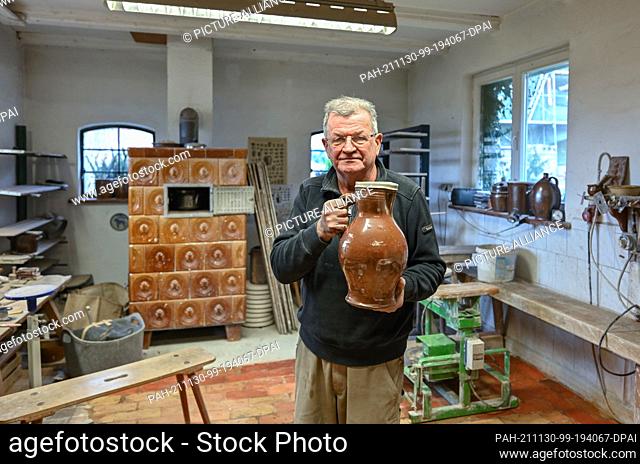 26 November 2021, Brandenburg, Groß Neuendorf: Manfred Dannegger, potter, stands in his workshop holding a jug in his hands