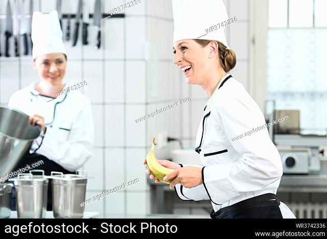 Two female chefs in gastronomic kitchen wearing white cooking uniforms