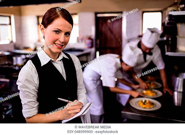Female waitress noting an order on notepad in kitchen