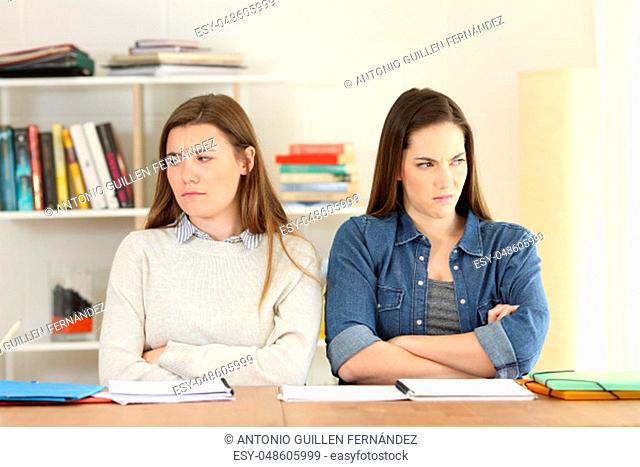 Front view of two angry students looking ignoring each other at home