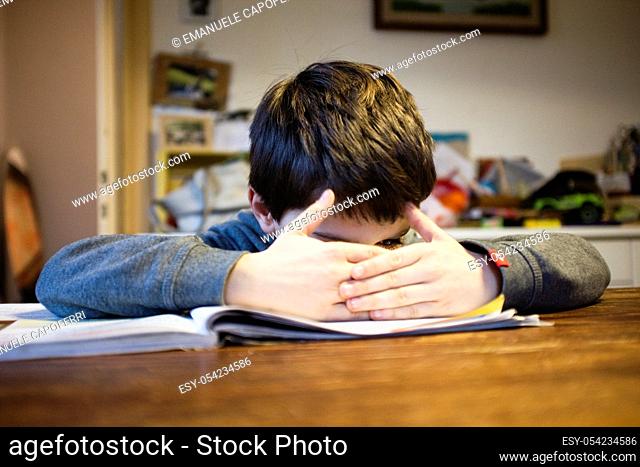 child sitting at the table in the kitchen at home with book