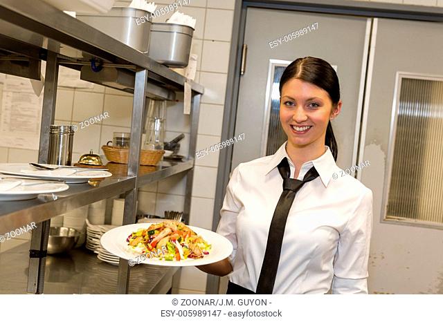 Smiling waitress serving salad on plate