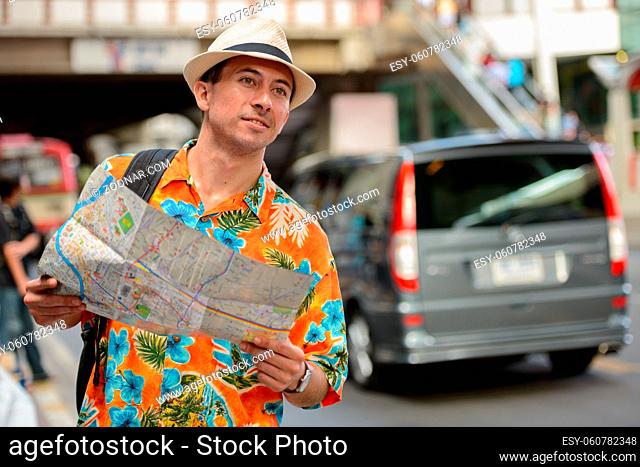 Portrait of young handsome tourist man in the city streets outdoors