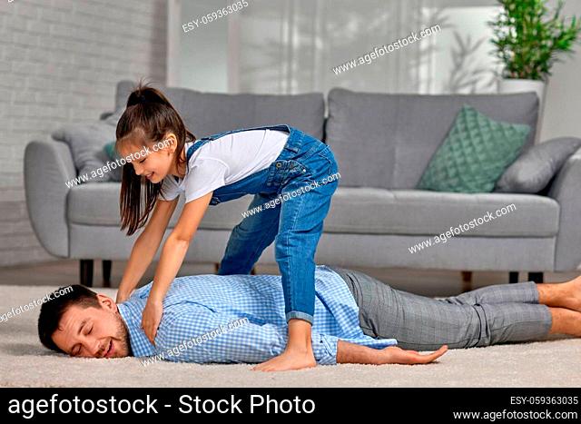 happy little child daughter doing massage to father at home. Father's day