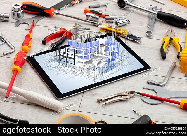 Tablet with construction tools and 3d house plan concept