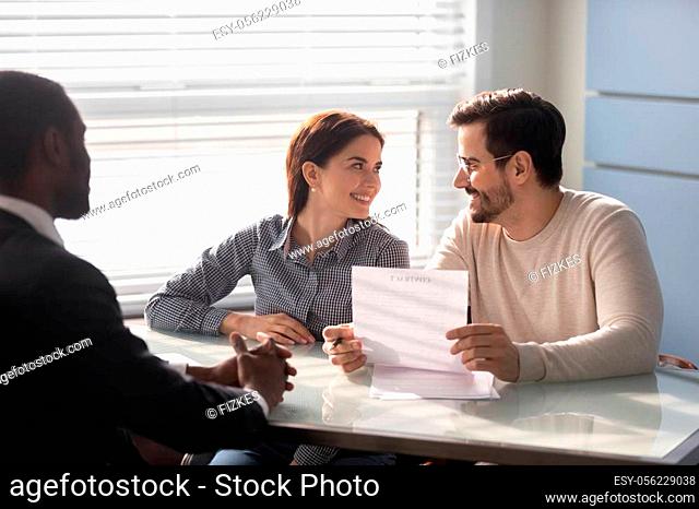 Happy family couple clients meeting african american financial consultant lawyer bank worker. Smiling married spouse buyers discussing contract details before...