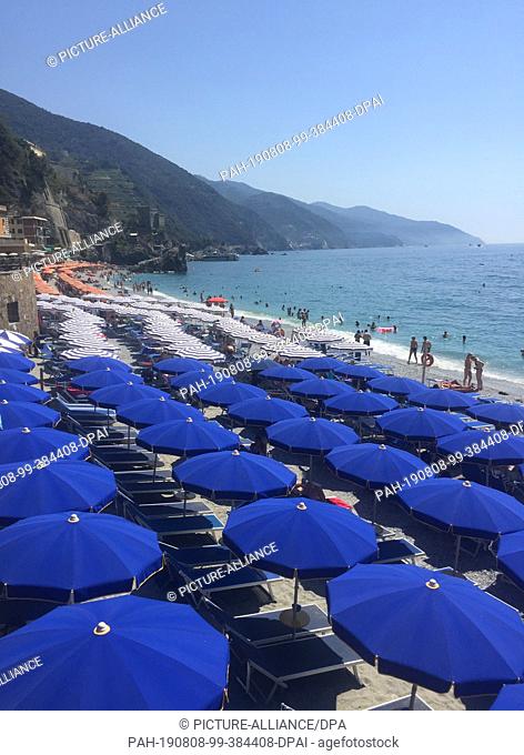 FILED - 05 August 2017, Italy, Cinque Terre: There are numerous sunshades on the beach of the Italian Riviera. Some tourists get involved in too daring things...