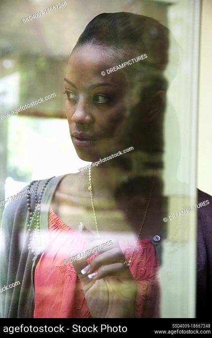 Portrait of an African American woman standing at a window looking out