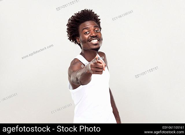 Hey you! Man in white t-shirt showing finger at camera. Studio shot. Gray background