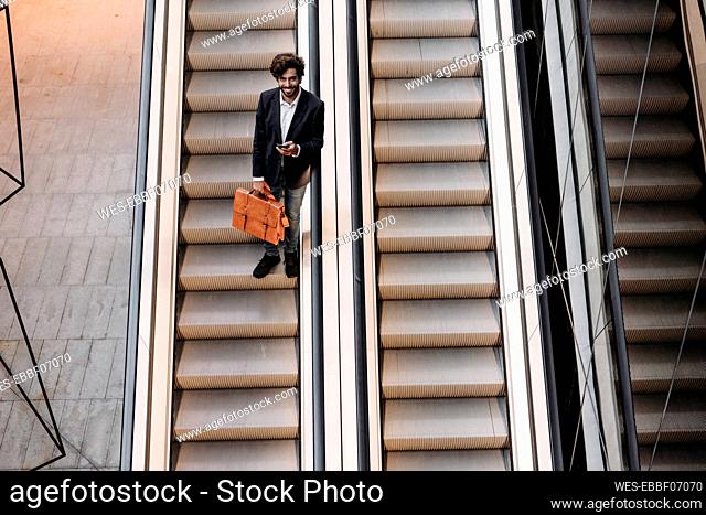 Smiling businessman moving down from escalator