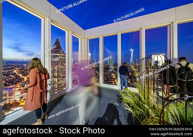 27 September 2023, Hesse, Frankfurt/Main: Visitors stand on the roof terrace of the Sky Bar of the ""now Hotel Frankfurt"" at the ""Blue Hour""