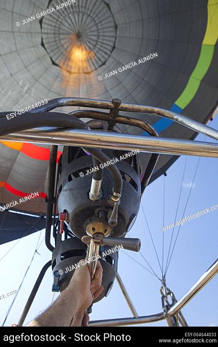 Hot air balloon pilot operating the burners. Low angle inside view