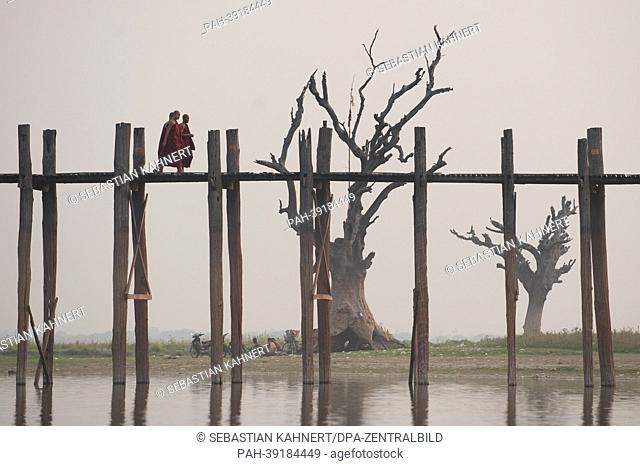 Three Buddhist monks walk across the U Bein Bridge on the Taungthaman Lake in Amarapura, Myanmar, 02 April 2013. Photo: Sebastian Kahnert | usage worldwide