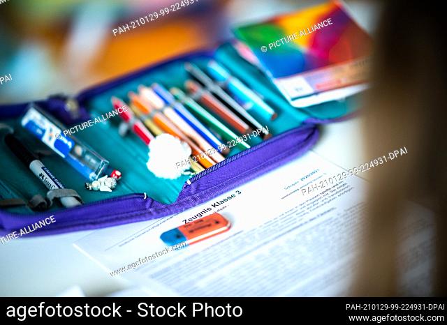 29 January 2021, North Rhine-Westphalia, Wetter: ILLUSTRATION - A third grade student looks at her report card lying on her desk