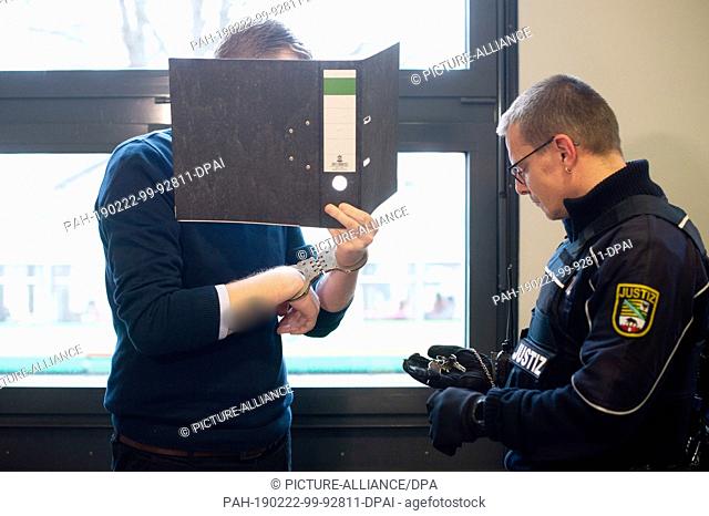 22 February 2019, Saxony-Anhalt, Magdeburg: The defendant (l) is standing in front of a justice officer in the district court who is looking for the key for the...