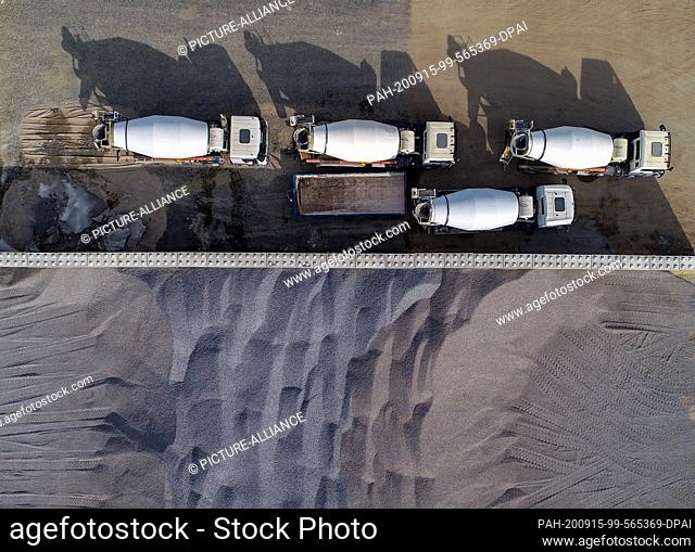 13 September 2020, Brandenburg, Grünheide: Concrete transporters stand next to a sand storage area on the Tesla Gigafactory construction site (aerial view with...